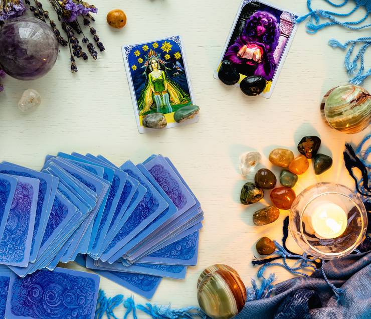 Minsk, Belarus - February 2022: star and priestess cards in tarot divination with candles and stones on a light table with dried flowers and a blue tablecloth. Magic and the occult